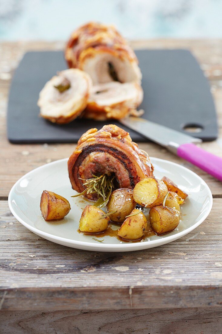 Stuffed roast pork roll with herbs and roast potatoes