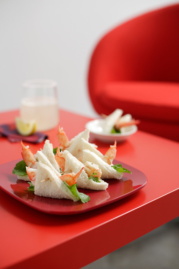 Roter Teller mit Garnelen-Sandwiches auf rotem Tisch
