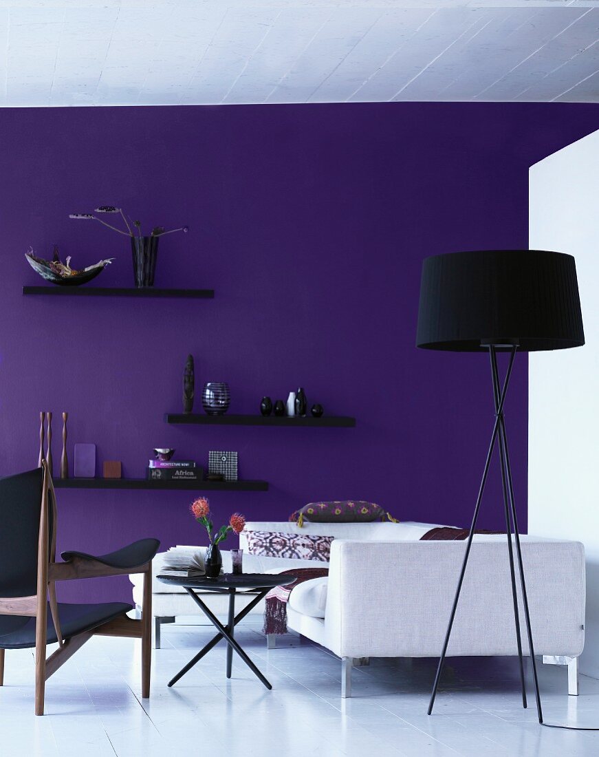 Showroom -schwarze Stehlampe und weisses Sofa vor violett getönter Wand