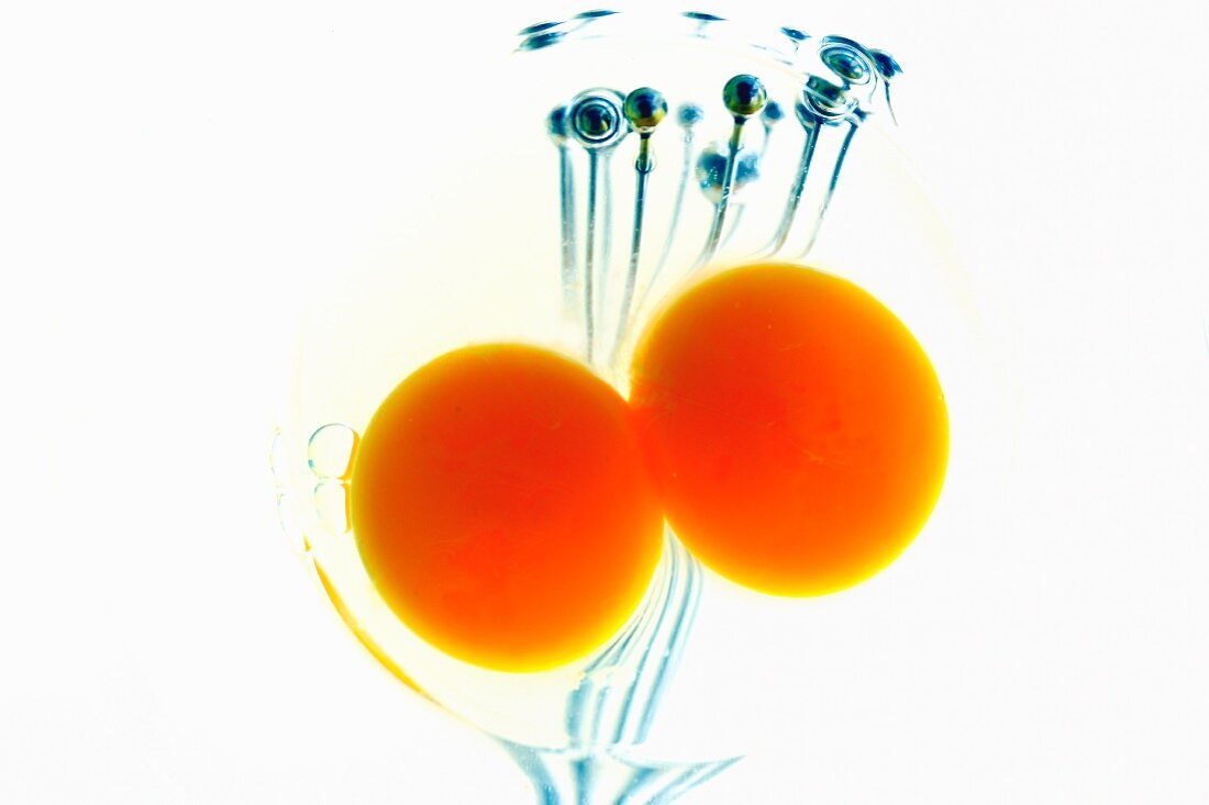Two egg yolks and a whisk