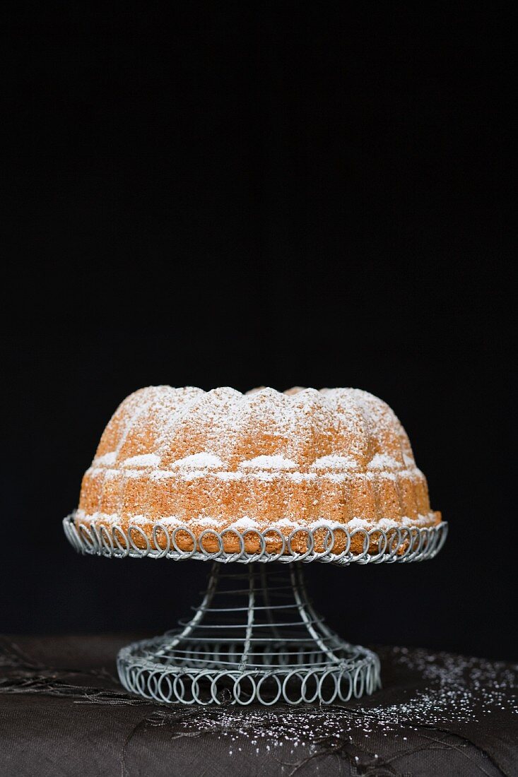 A Madeira Bundt cake decorated with icing sugar on a cake stand