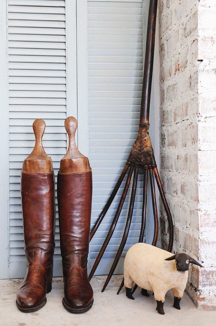 Riding boots, pitchfork and wooden sheep figurine