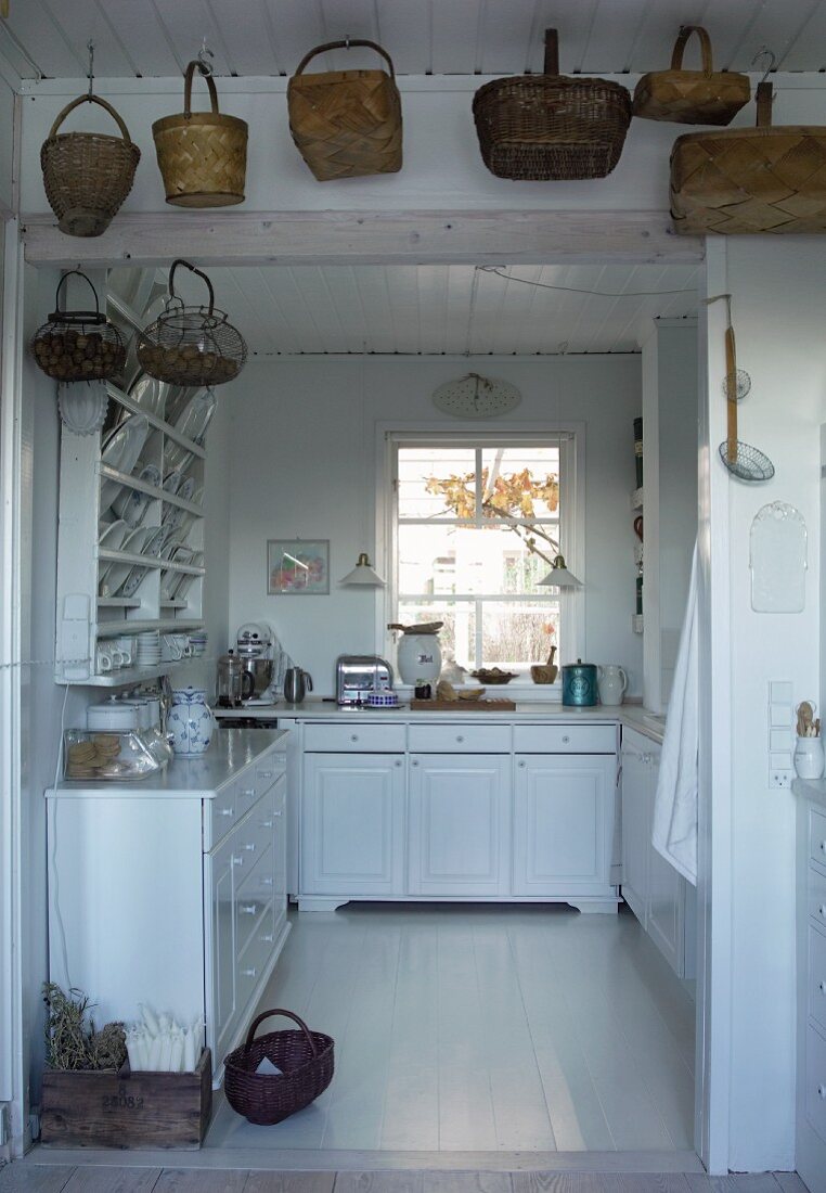 Baskets hanging above open doorway leading to country house kitchen