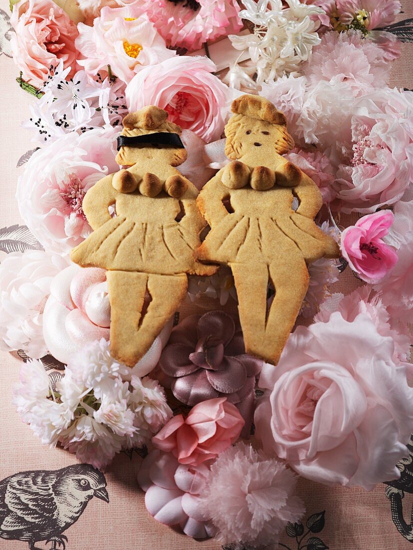 Two lady-shaped biscuits on a bed of flowers