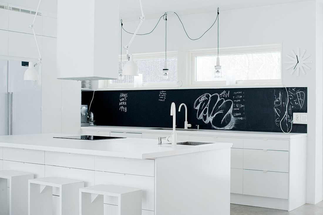 weiße Designerküche mit schwarzem Spritzschutz; Kochinsel mit Barhockern aus einfachen Holzrahmen