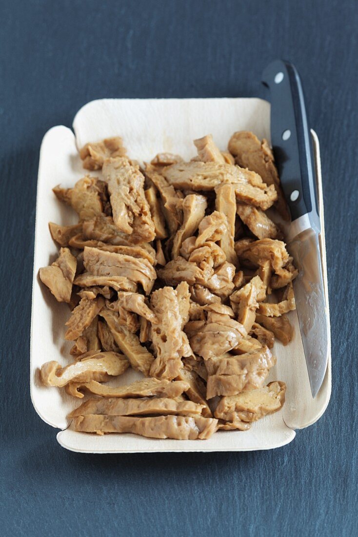 A bowl of seitan with a knife