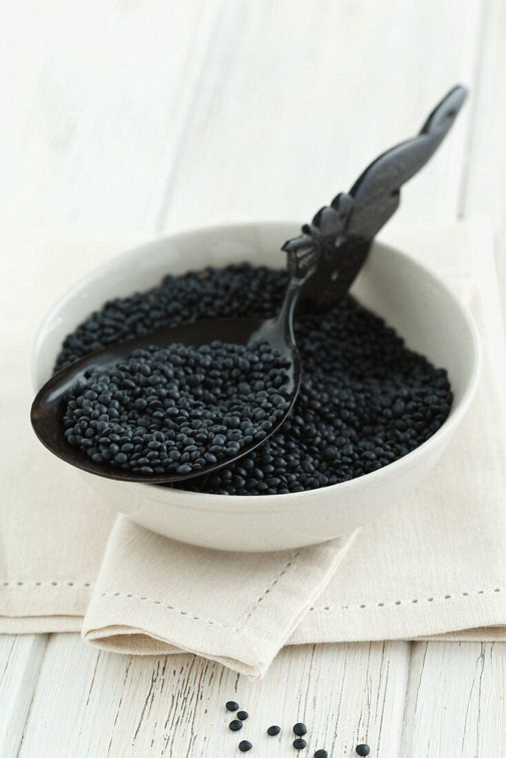 Black lentils in a bowl with a spoon