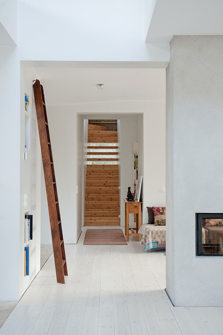 View through floor-to-ceiling doorway of wooden staircase in minimalist interior with white wooden floor