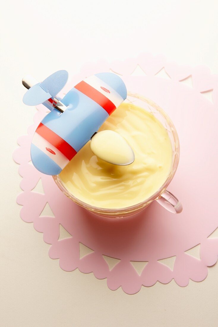 Vanilla pudding and a spoon decorated with a toy airplane