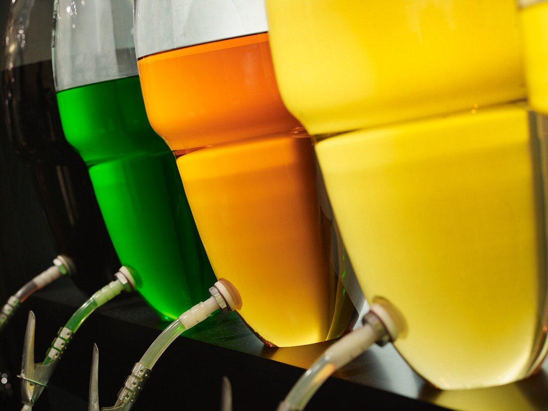 Verschiedenfarbige Essenzen in Glasbottichen: Trüffellikör, Absinth, Rum, Cognac