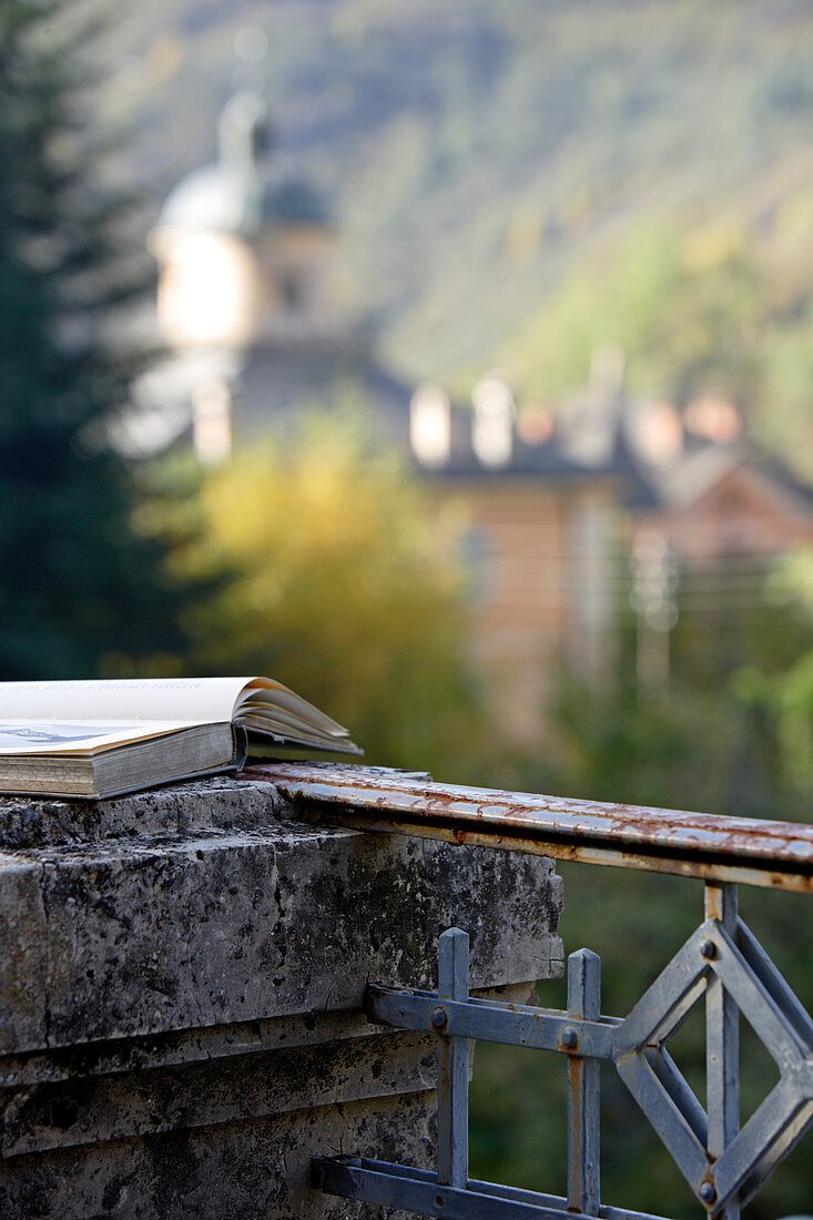 Buch liegt auf verwittertem Steinpfeiler einer Dachterrasse