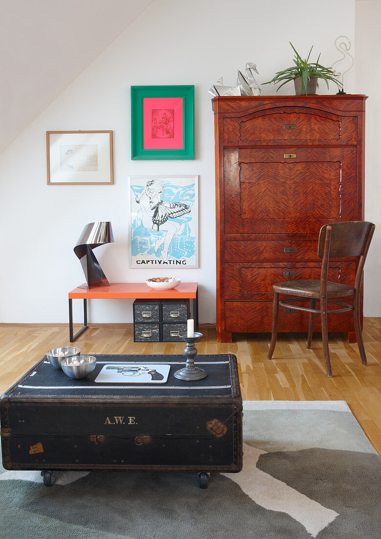 Original coffee table made from vintage trunk on castors; antique bureau and pictures on wall in background