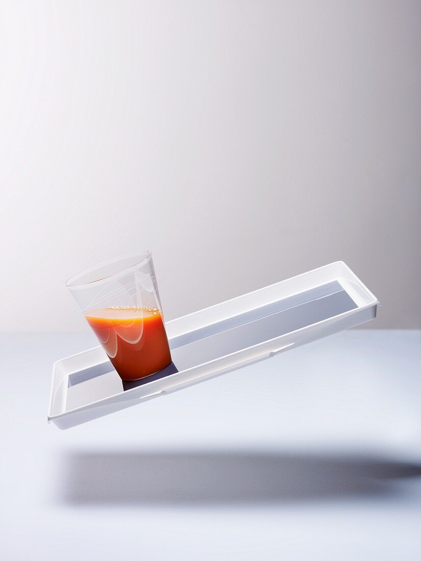 A glass of carrot juice on a tilted tray