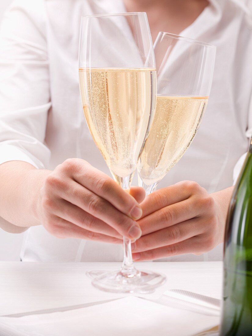 Hände halten zwei Gläser mit Champagner