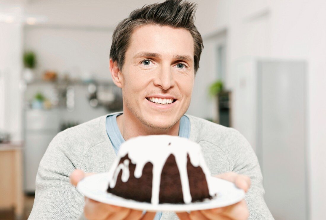 Mann serviert Schokoladenkuchen mit Zuckerguss