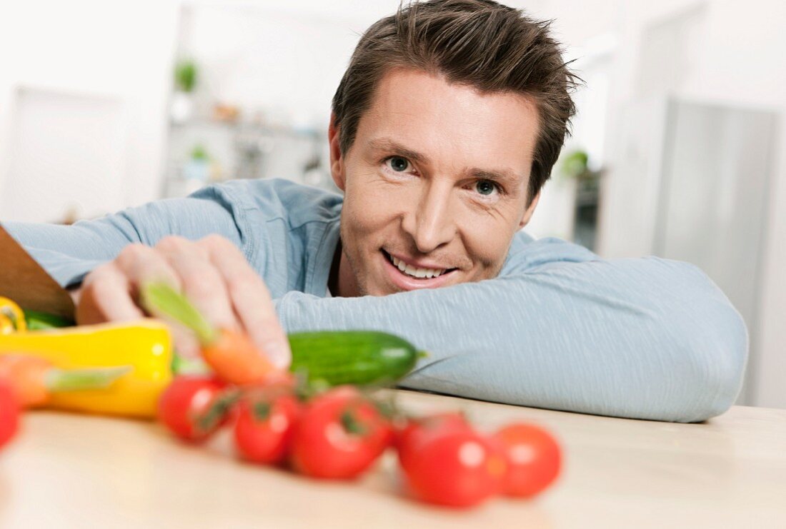 A man sitting at a kitchen table with fresh vegetables