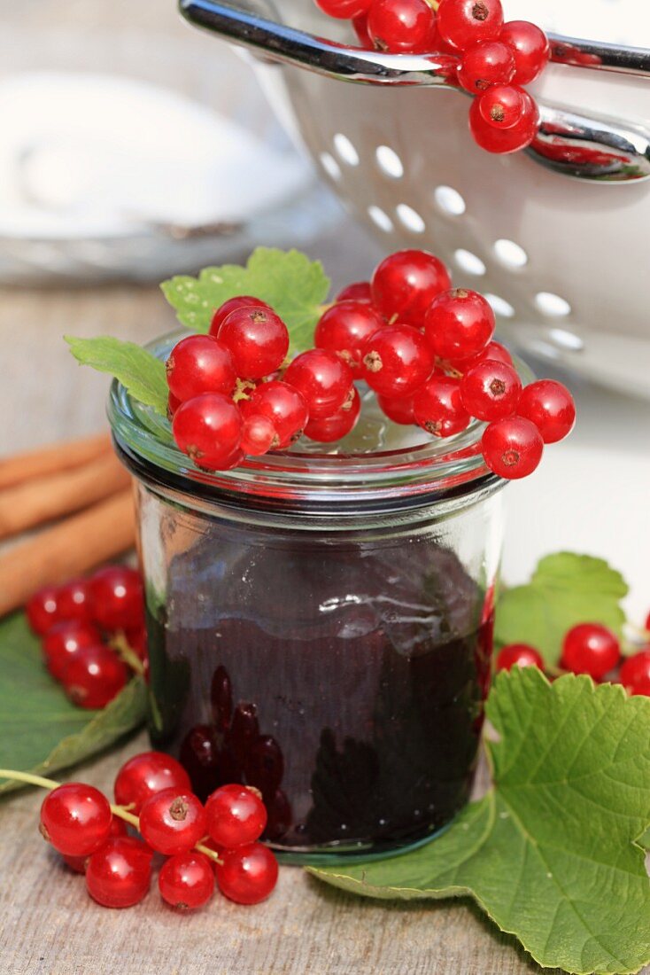 A glass of red currant marmalade and fresh red currants