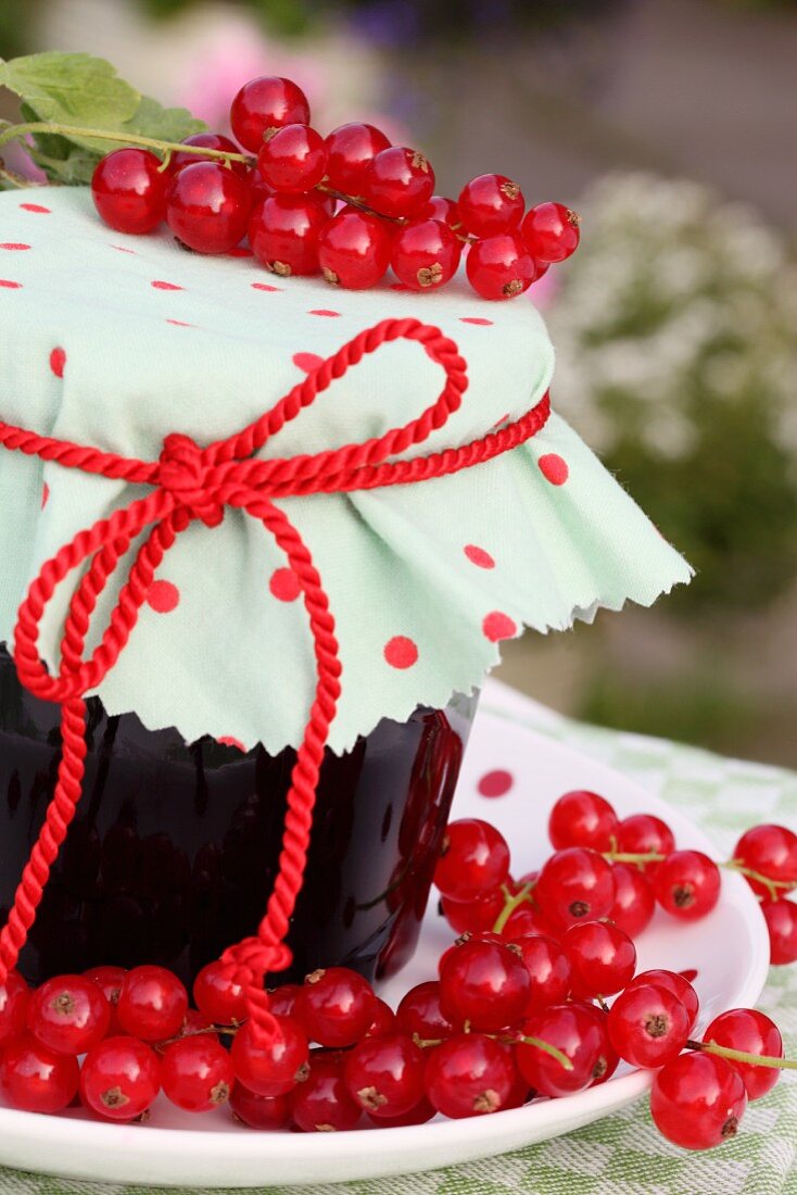 Ein Glas Johannisbeermarmelade und rote Johannisbeeren