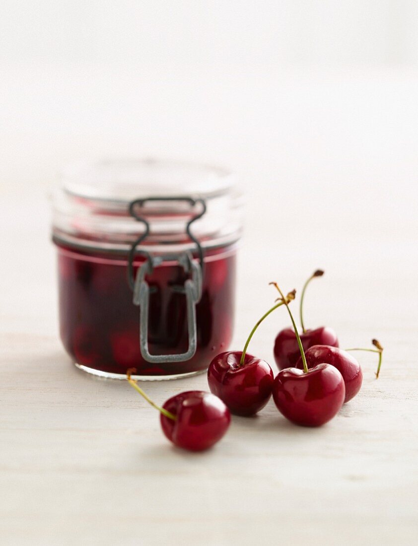 A jar of cherry jam and fresh cherries