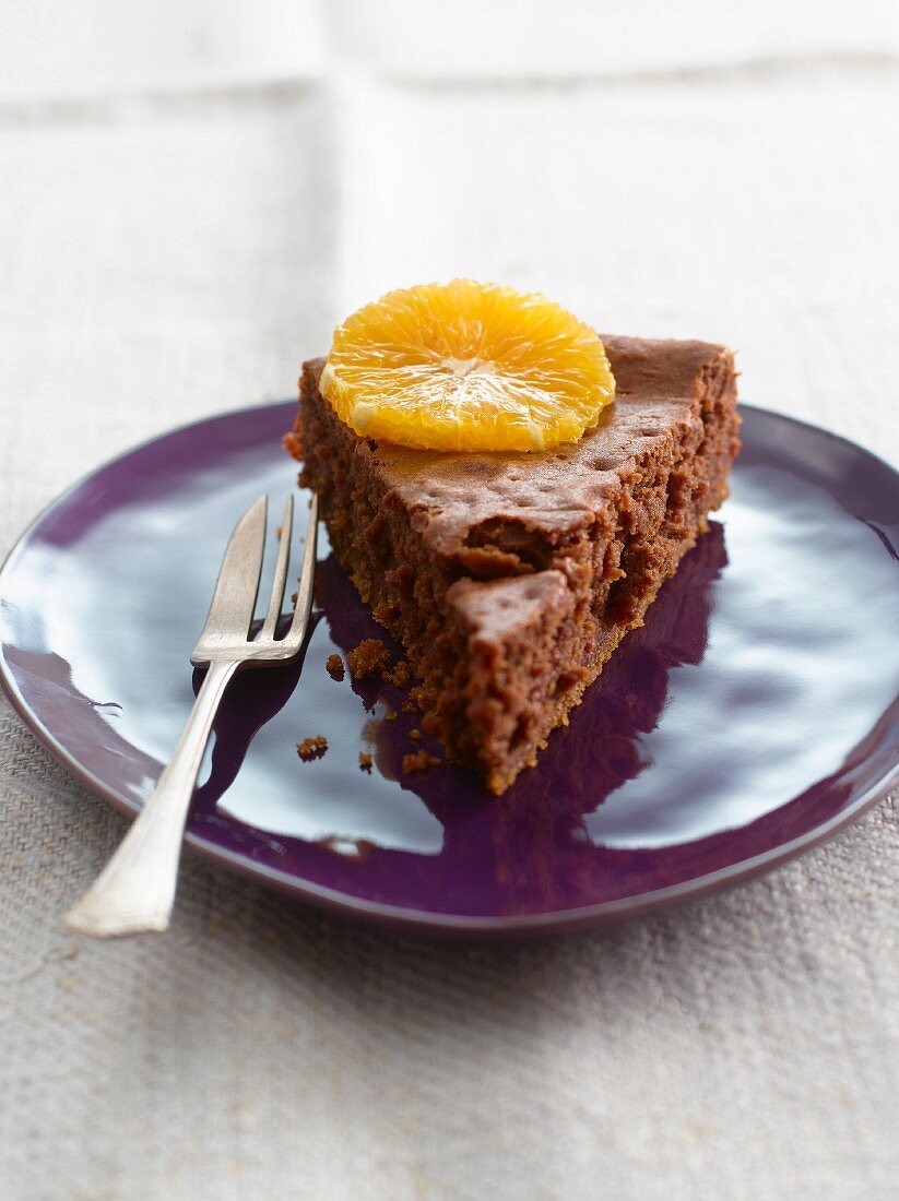 A slice of brownie cake topped with an orange slice