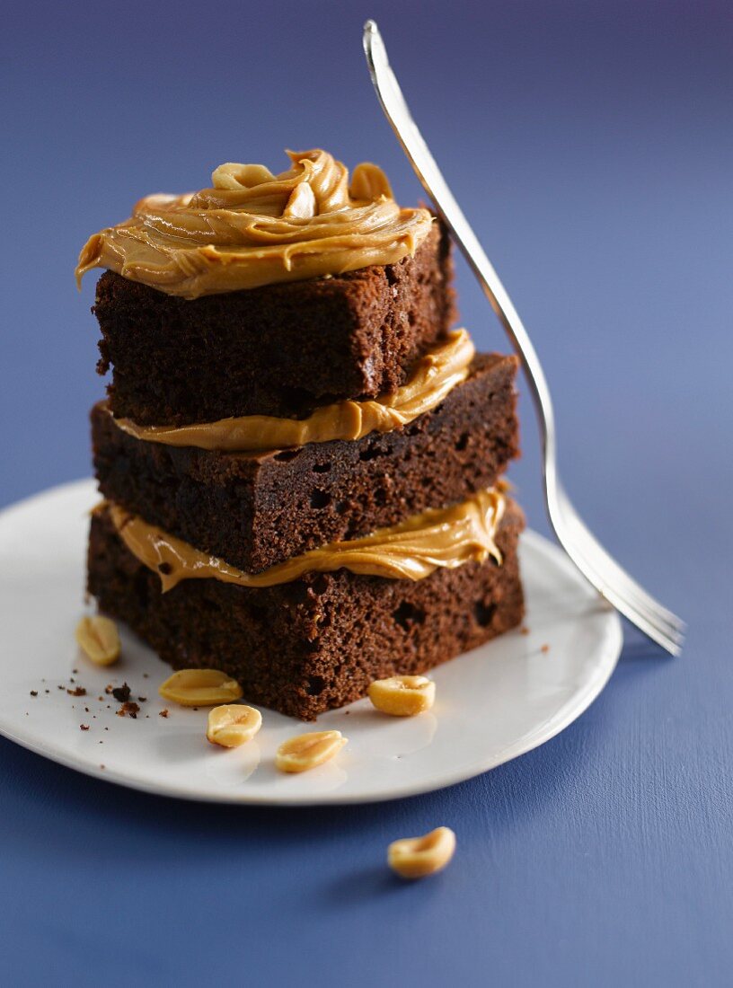 A stack of brownies topped with peanut butter