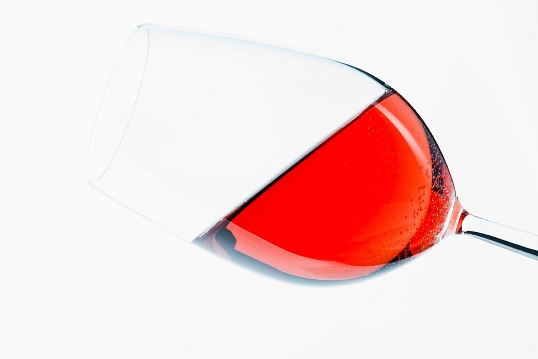 A glass of red wine held at an angle