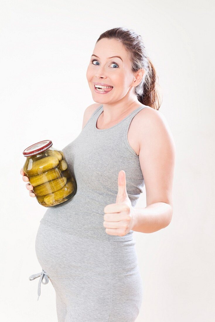 Schwangere Frau hält ein Glas Essiggurken