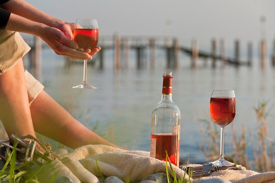 A woman on the bank of a lake with rose wine