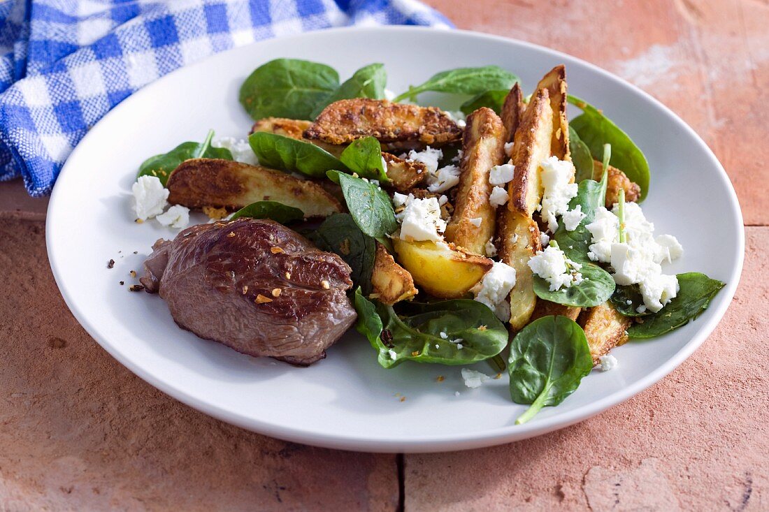 Lamb fillet on a warm potato salad with spinach and feta cheese
