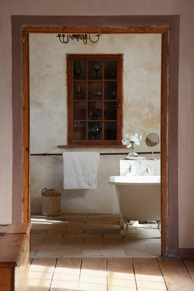 View from anteroom of cabinet with glass and lattice door built into niche in rustic bathroom