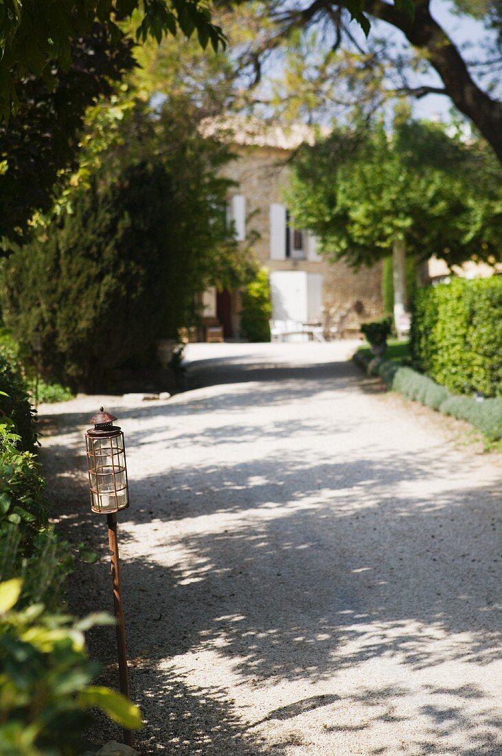 Lantern on sunny driveway in Mediterranean complex with rustic farmhouse