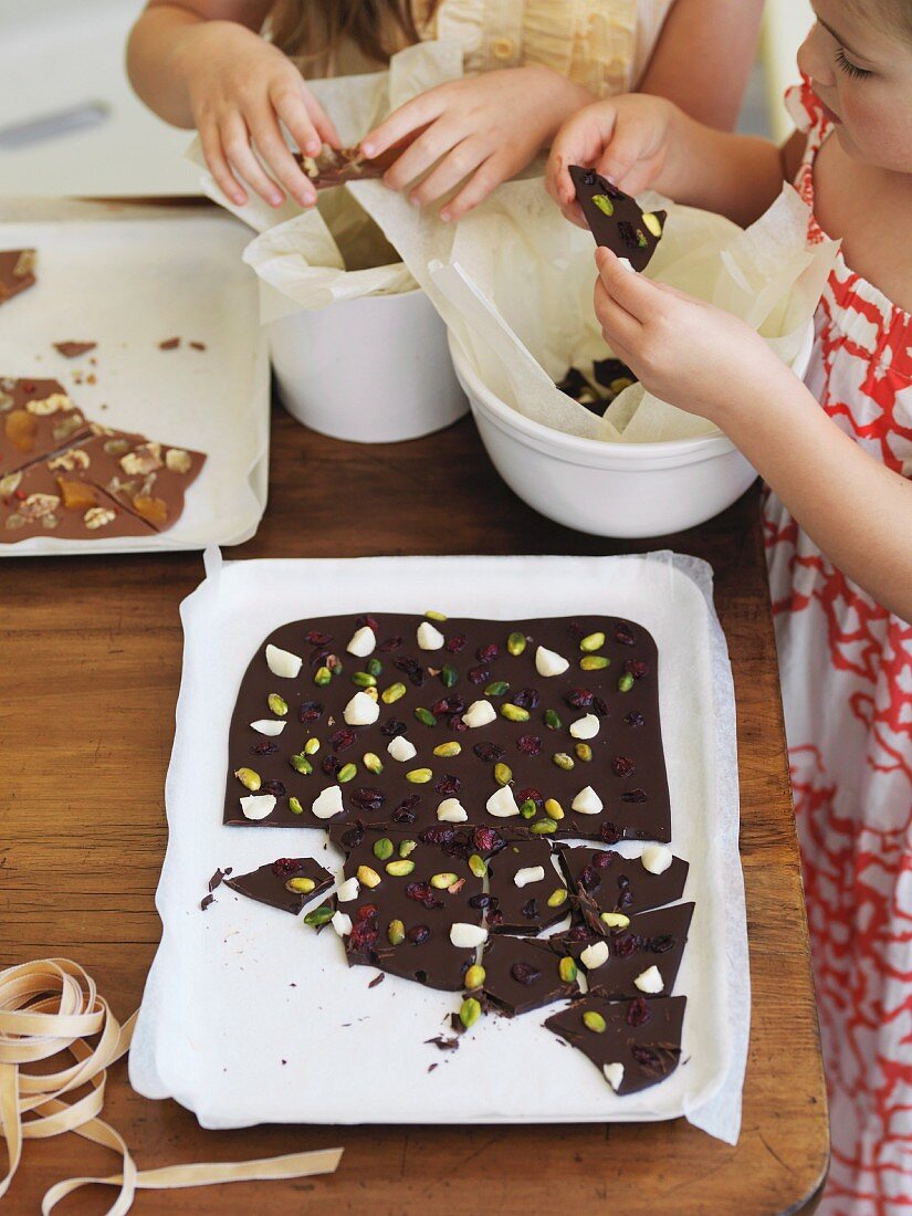Kinder zerbrechen Schokolade mit Nüssen und Trockenfrüchten