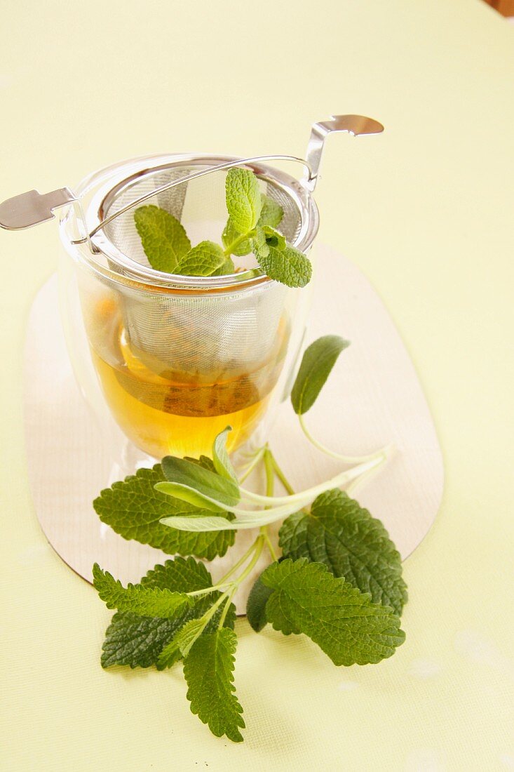 A glass of herb tea and a tea strainer