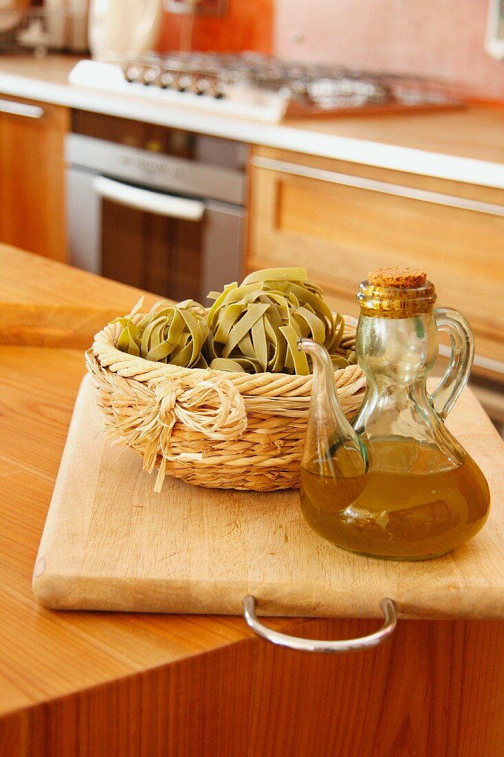Bandnudeln in einem Körbchen und Olivenöl in einem Glaskännchen
