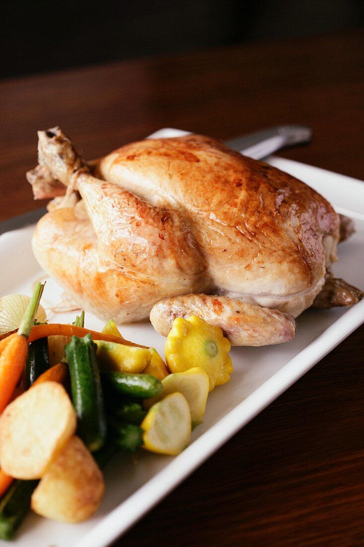 A whole roast chicken with a side of vegetables