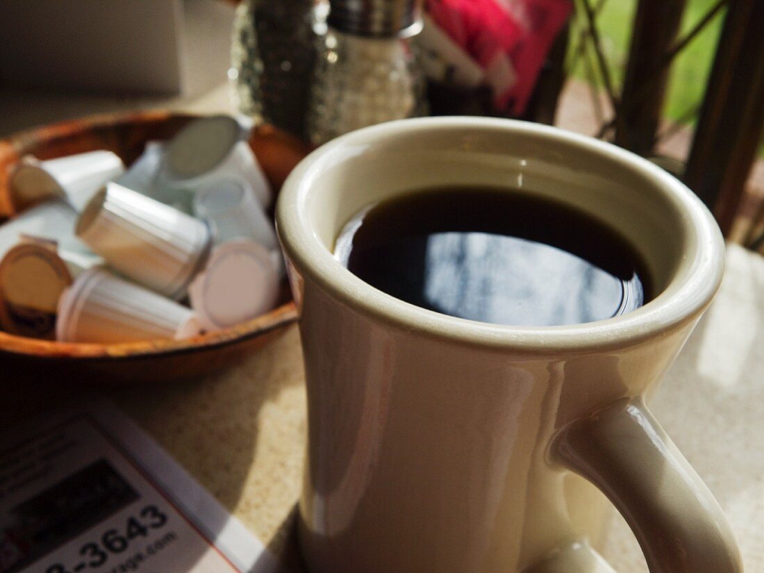 Cup of Black Coffee on a Cafe Table with a Bowl of Cream