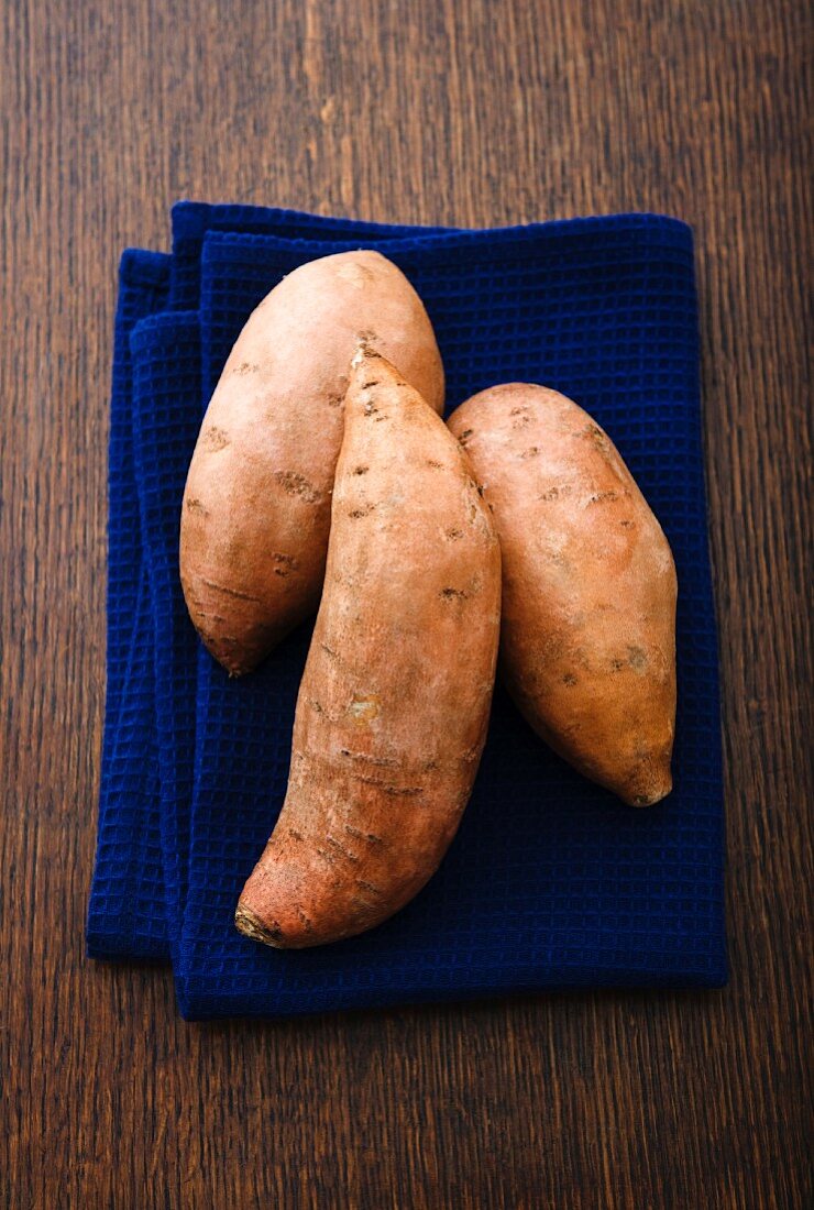 Three sweet potatoes on a tea towel