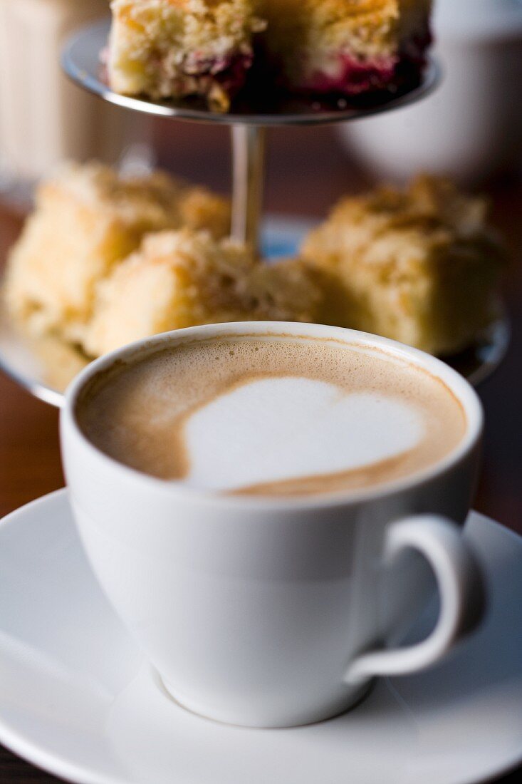 Cappuccino mit Herz vor Kuchenetagere