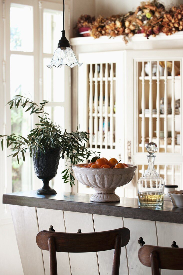 Olive branches, fruit and liqueur on counter in Provencal kitchen