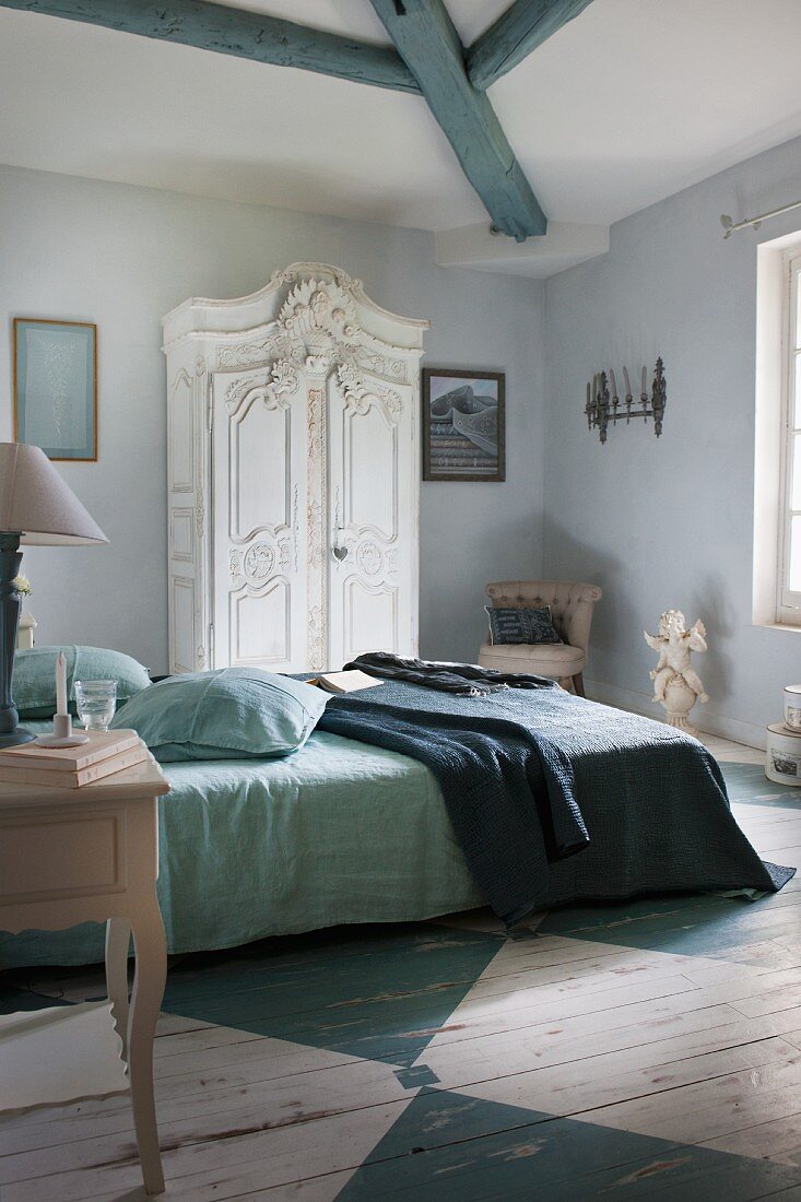 Ländliches Schlafzimmer mit weisserm Kleiderschrank und blau-weiss bemaltem Holzboden