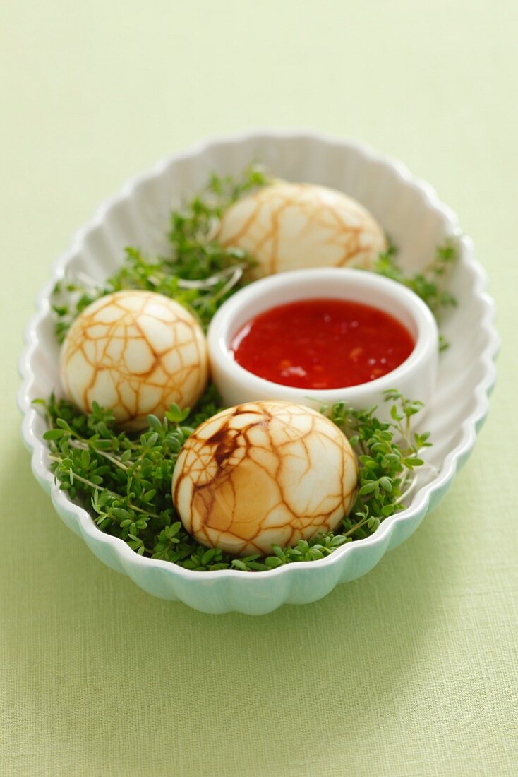 Eggs boiled in tea on a bed of cress with chilli sauce (China)