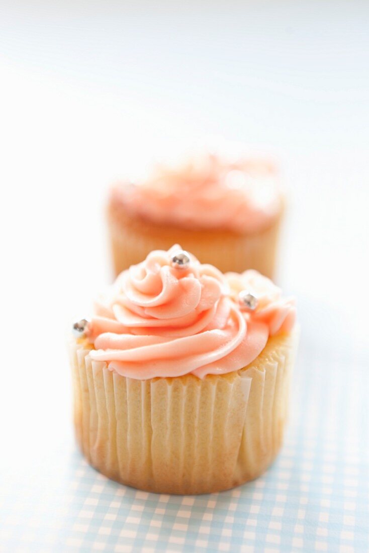 Cupcakes topped with pink frosting and silver balls