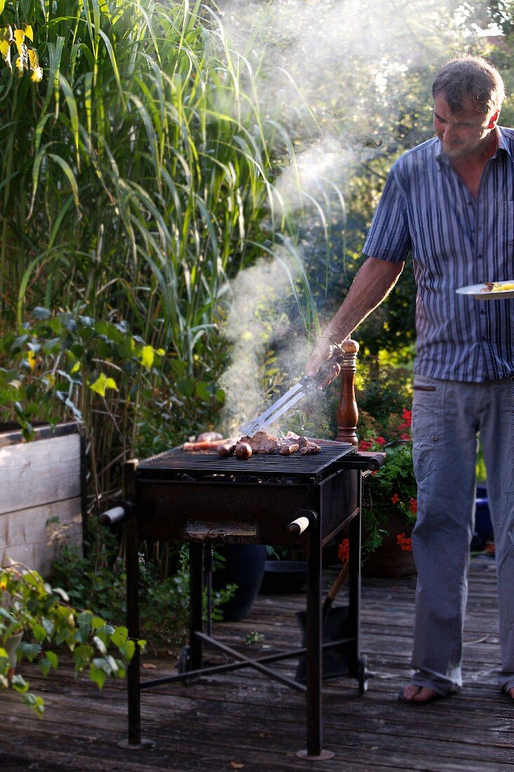 Mann beim grillen auf der Terrasse