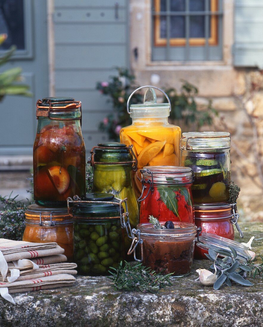 Eingemachtes Obst & Gemüse in Gläsern auf Mauer im Freien