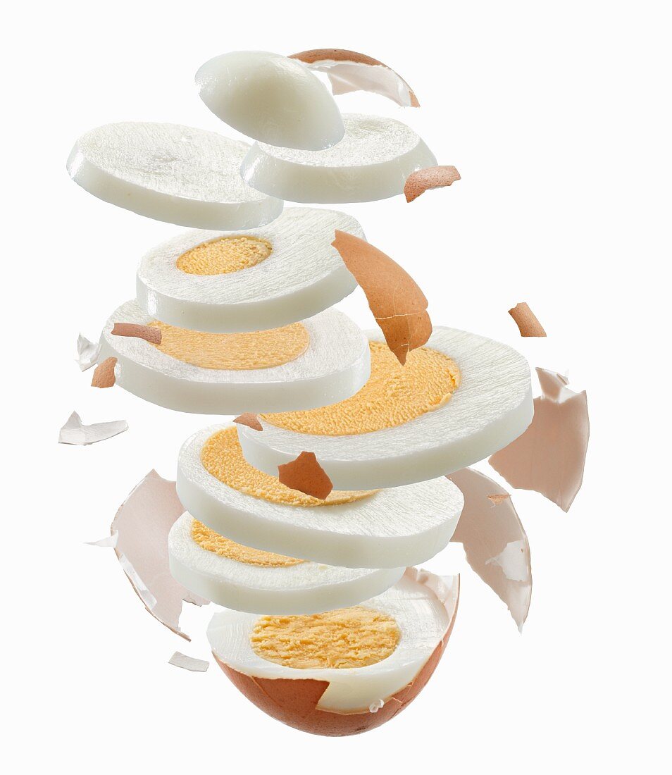 Sliced hard-boiled egg and egg shell flying through the air