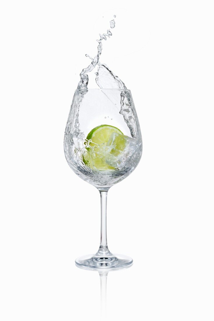 A lime slice falling into a glass of water