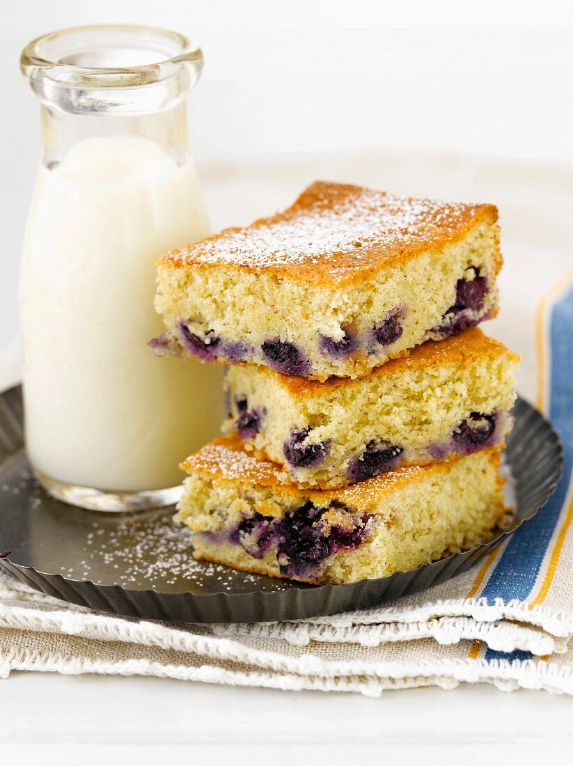 Squares of Blueberry Buckle Cake Stacked with a Bottle of Milk