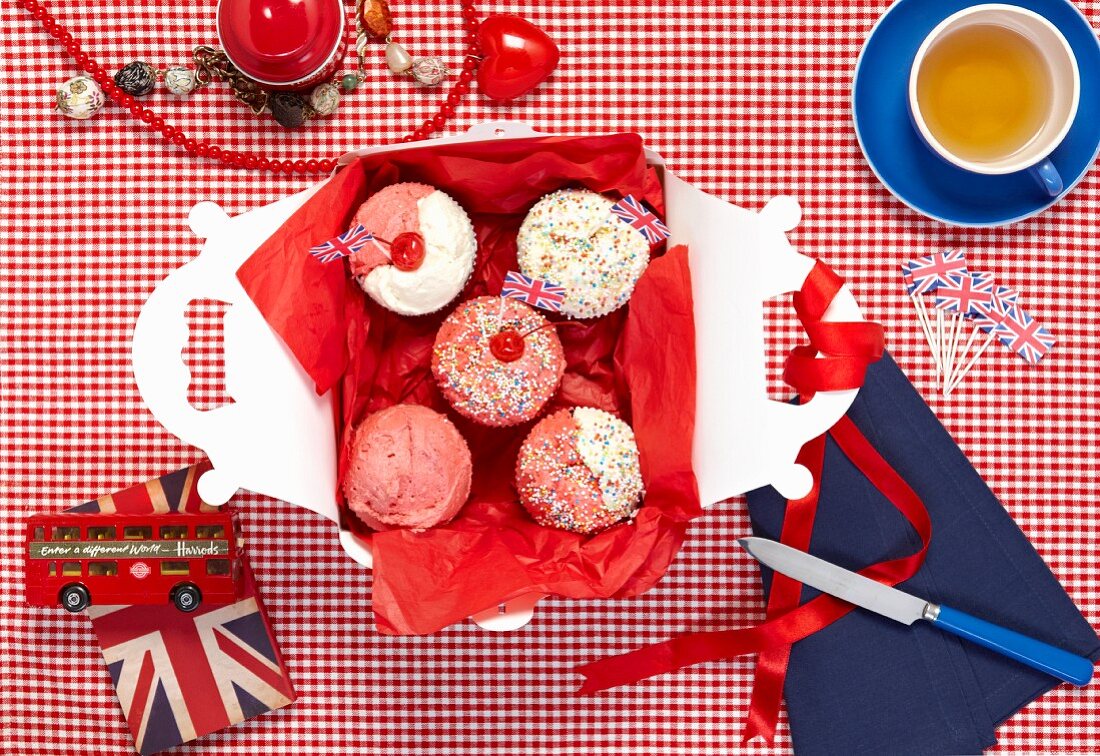 Cupcakes with Union Jacks in a box and a cup of tea