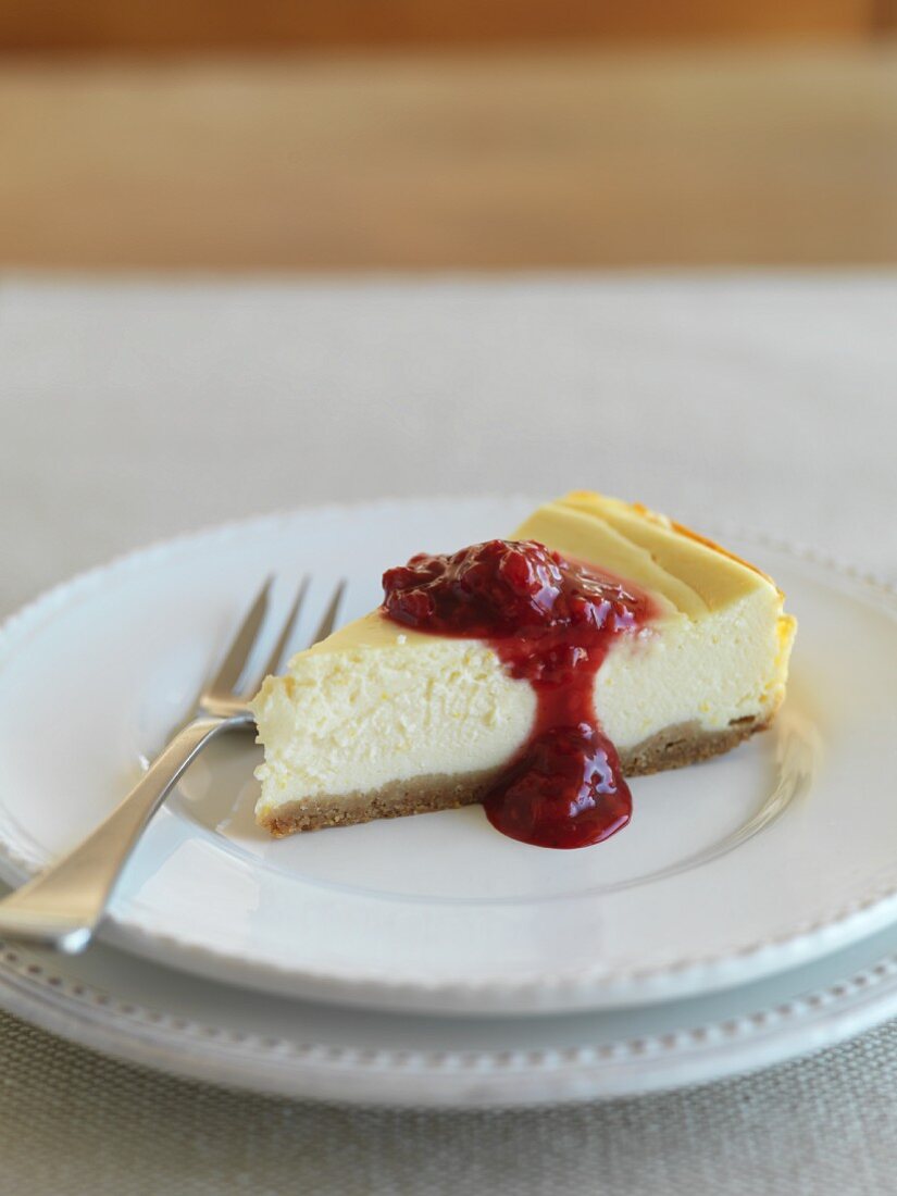 A slice of ricotta cake with berry sauce