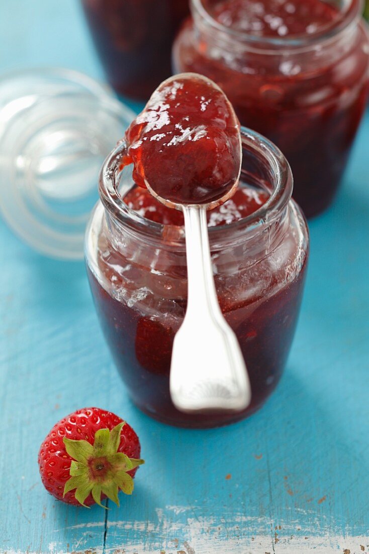 Strawberry jam in a jar and on a spoom